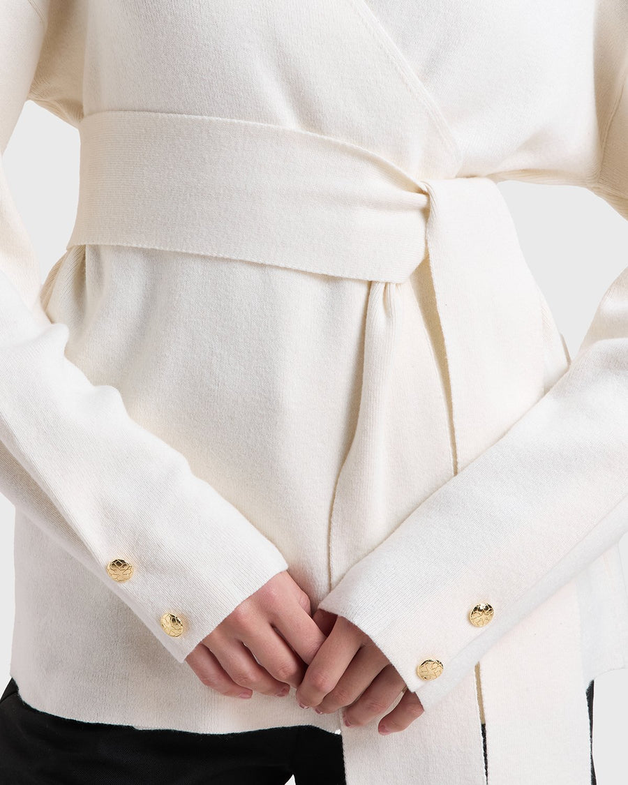 Cream soft wrap knit cardigan styled close up with Nawa's gold signature buttons