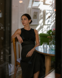 A woman wearing a sleeveless Nawa black ribbed knit tank with Grey high-waisted midi skirt with a structured yoke that holds its place through the day. 