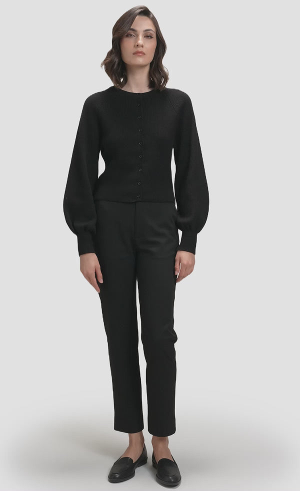 Model wearing black ribbed knit button cardigan with balloon sleeves over black wide-leg trousers
